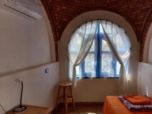 Dormitorio con ventana, cama y taburete en Nubian Lotus en Asuán