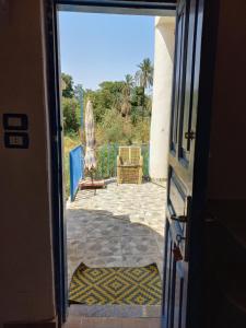 an open door to a patio with an umbrella and a chair at Nubian Lotus in Aswan