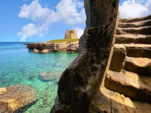 a stairway leading to the ocean with a rocky shore at La maison del porto in San Foca