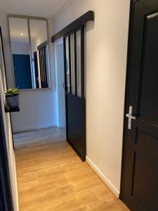 a hallway with a black door and a wooden floor at Les Jardins du Château in Châteauroux