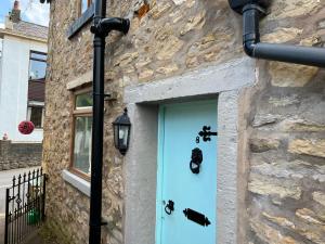 Whitebrook Cottage في Mellor: باب أزرق على مبنى حجري مع ضوء الشارع