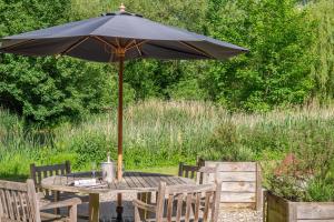 - une table en bois avec un parasol dans le jardin dans l'établissement Heavenly luxury rustic cottage in historic country estate - Belchamp Hall Mill, à Belchamp Otten