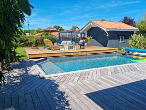 una piscina con terrazza e una casa di Villa climatisée avec piscine à LEGE CAP FERRET a Lège-Cap-Ferret