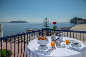 un tavolo con cibo e bevande su un balcone con vista sull'oceano di Punta Molino Beach Resort & Thermal Spa a Ischia