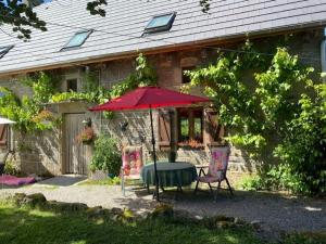 uma mesa e duas cadeiras com um guarda-sol em frente a uma casa em Maison de Campagne em Sarroux