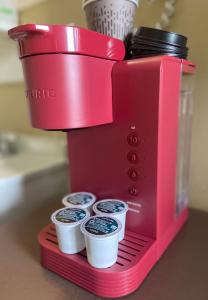 a red coffee maker with four cups on a counter at Motel Exquise in Coaticook