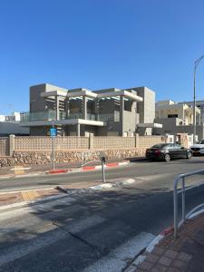 a street with cars parked in front of a building at שחף ברוזמרין in Eilat