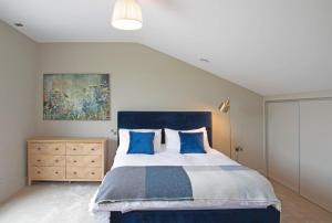 a bedroom with a blue and white bed and a painting at Ballymacooda House in Drumadrohid