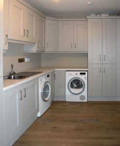 a kitchen with white cabinets and a washer and dryer at Ballymacooda House in Drumadrohid