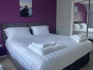 a large white bed with white towels on it at 3 Mackay Road in Dornoch