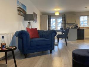 a living room with a blue couch and a kitchen at 3 Mackay Road in Dornoch
