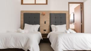 two beds in a hotel room with white sheets at Primavera Plus in Villavicencio