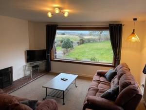 a living room with a couch and a large window at Baldovan Cottage in Dundee