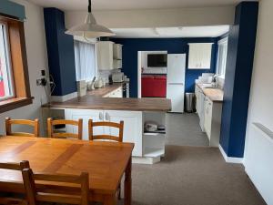 Baldovan Cottage في دندي: مطبخ مع طاولة خشبية وغرفة طعام