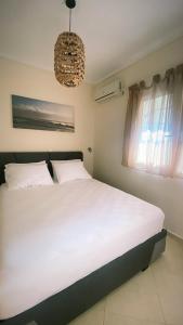 sypialnia z dużym białym łóżkiem i żyrandolem w obiekcie Elena apartment chalkidiki w mieście Kallithea
