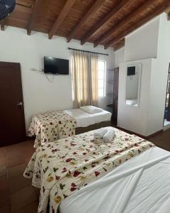 a hotel room with two beds and a television at Hotel ilama in Buga