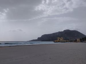 een uitzicht op een strand met een berg op de achtergrond bij Casabella Mondello in Mondello