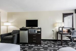 una camera d'albergo con TV, divano e sedia di Days Inn by Wyndham Oklahoma City Bricktown a Oklahoma City