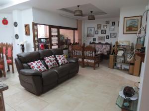 sala de estar con sofá de cuero y sillas en La Casa de Guadua, en Oiba