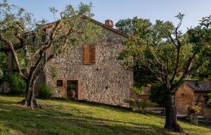 an old stone house with trees in front of it at Poggio dell' orso in Cetona