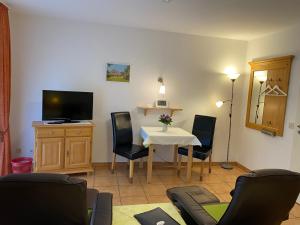 a living room with a table and chairs and a television at Landhaus Teuteberg in Bad Bevensen