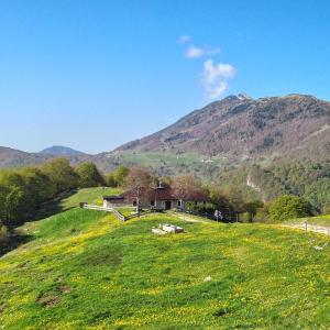 una casa en una colina de hierba con montañas en el fondo en Rifugio Baita Fos-Ce, en Brentonico