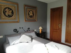 1 dormitorio con 1 cama blanca y 2 cuadros en la pared en Habitación en casa cerca de la playa, en Sada