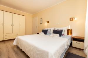 sypialnia z dużym białym łóżkiem z poduszkami w obiekcie Villa Teresa w miejscowości Mali Lošinj