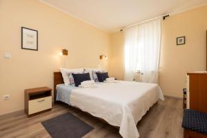 sypialnia z dużym białym łóżkiem i oknem w obiekcie Villa Teresa w miejscowości Mali Lošinj