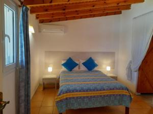 a bedroom with a bed with blue pillows at Katia cottage Kassiopi in Kassiopi