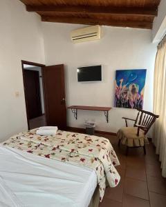 - une chambre avec un lit, une télévision et une chaise dans l'établissement Hotel ilama, à Buga