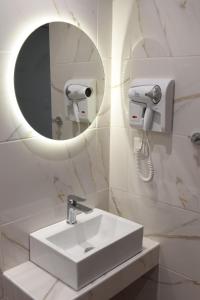 a white bathroom with a sink and a mirror at Hotel Lefkes in Paralía Skotínis