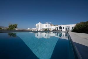 Villa Amarone في مدينة ميكونوس: مسبح بمياه زرقاء امام مباني بيضاء