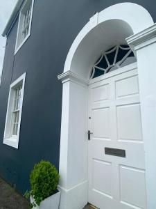 una porta bianca su un edificio blu con finestra di Dovenby Apartment- great base for exploring Lake District a Cockermouth