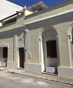 um edifício branco com duas janelas e uma porta em Lu Caleddhu em Specchia