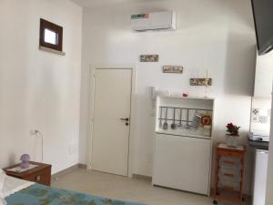eine Küche mit einer weißen Tür und einem Kühlschrank in der Unterkunft Lu Caleddhu in Specchia