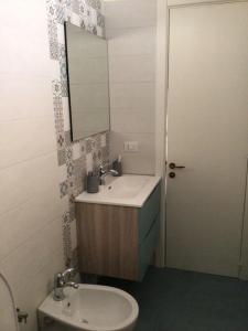 uma casa de banho com um lavatório, um espelho e um WC. em Lu Caleddhu em Specchia