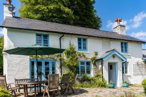 un cottage bianco con tavolo, sedie e ombrellone di Finest Retreats - Valley Cottage a Withypool