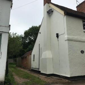 a white building with two doors on the side of it at Village period cottage in Wolston