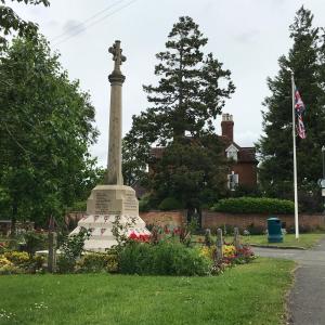 un monumento en un parque con una bandera y flores en Village period cottage, en Wolston