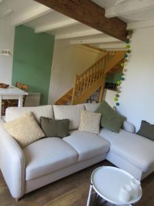 a living room with a white couch and stairs at Les vieilles pierres in Aumagne