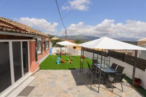 eine Terrasse mit einem Tisch, Stühlen und einer Liegewiese in der Unterkunft Family Country House-Corfu Holidays in Kanakádes