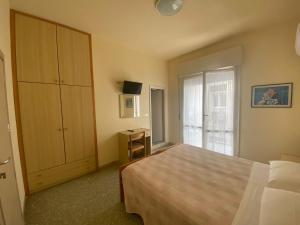 - une chambre avec un lit, une armoire et une fenêtre dans l'établissement Hotel Soave, à Cervia