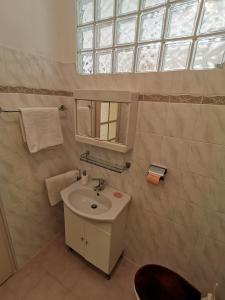 a white bathroom with a sink and a window at Apartment Grzin in Lovran