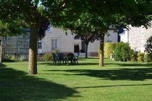 eine Liegewiese mit Stühlen und Bäumen vor einem Haus in der Unterkunft LES CHAMBRES D HOTES DU LAVOIR in Restigné