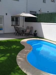 een zwembad in een tuin met een tafel en een parasol bij Casa Cristy in Montejaque
