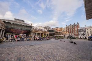 a crowd of people sitting in a plaza in a city at Stylish Covent Garden Apartments in London