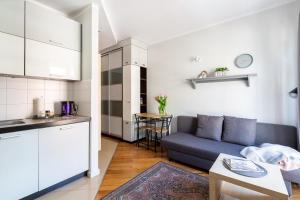 a living room with a blue couch and a kitchen at Apartament Kowalska Starówka in Elblag