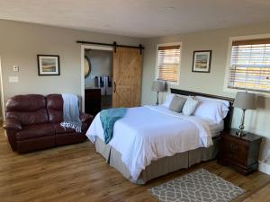 een slaapkamer met een bed, een bank en een stoel bij Alma Shore Lane Suites & Cottages in Alma