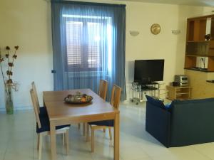 sala de estar con mesa, sillas y TV en Residenza Caserta Sud - Appartamento con giardino en Caserta